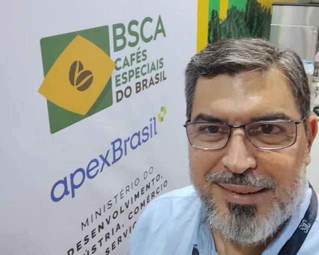 Fernando Reis ao lado do estande da BSCA, Cafés Especiais do Brasil, numa feira de café